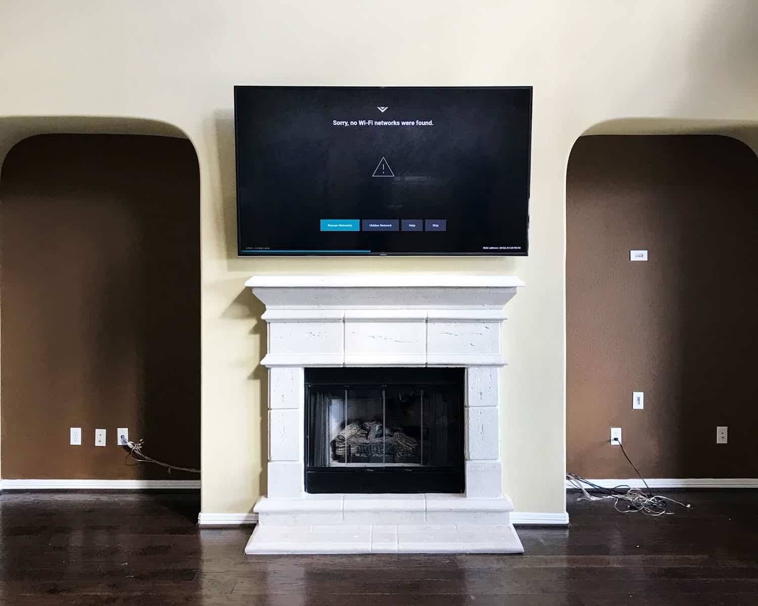 TV mounted above a white stone fireplace between two archways, mid-setup with a Wi-Fi connection screen showing
