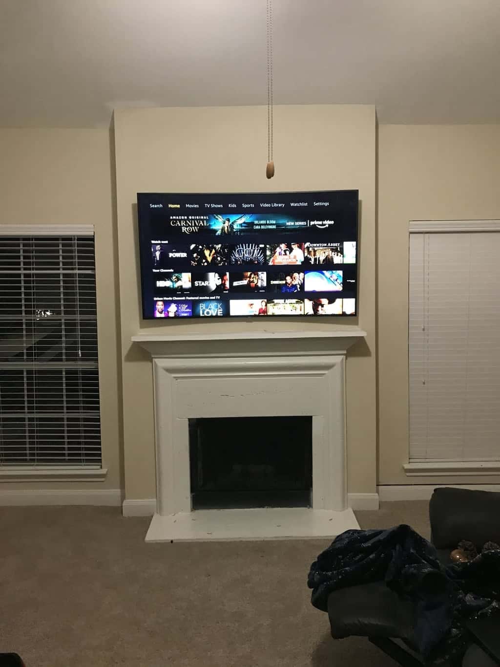 TV mounted above a white fireplace mantel displaying the Amazon Prime Video home screen