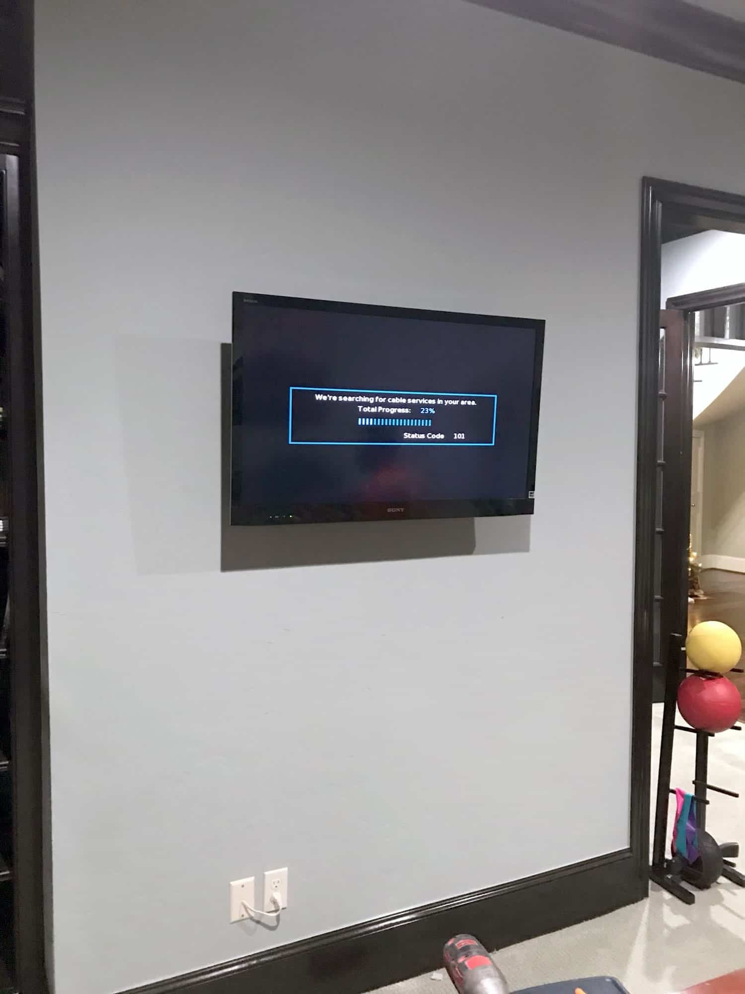 TV mounted on a wall displaying a cable box setup screen in a home gym area