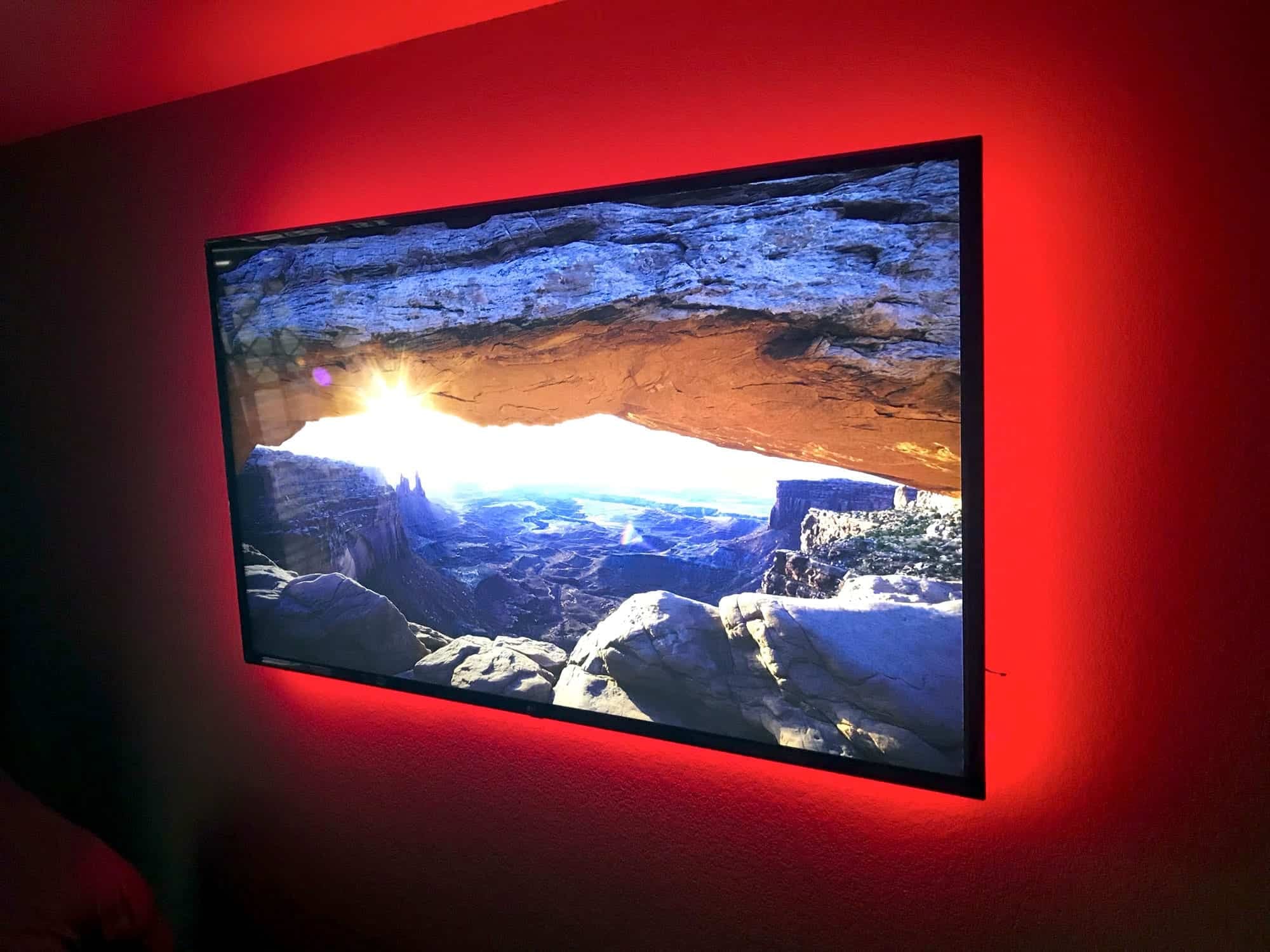 Wall-mounted TV with red LED backlighting displaying a desert canyon landscape