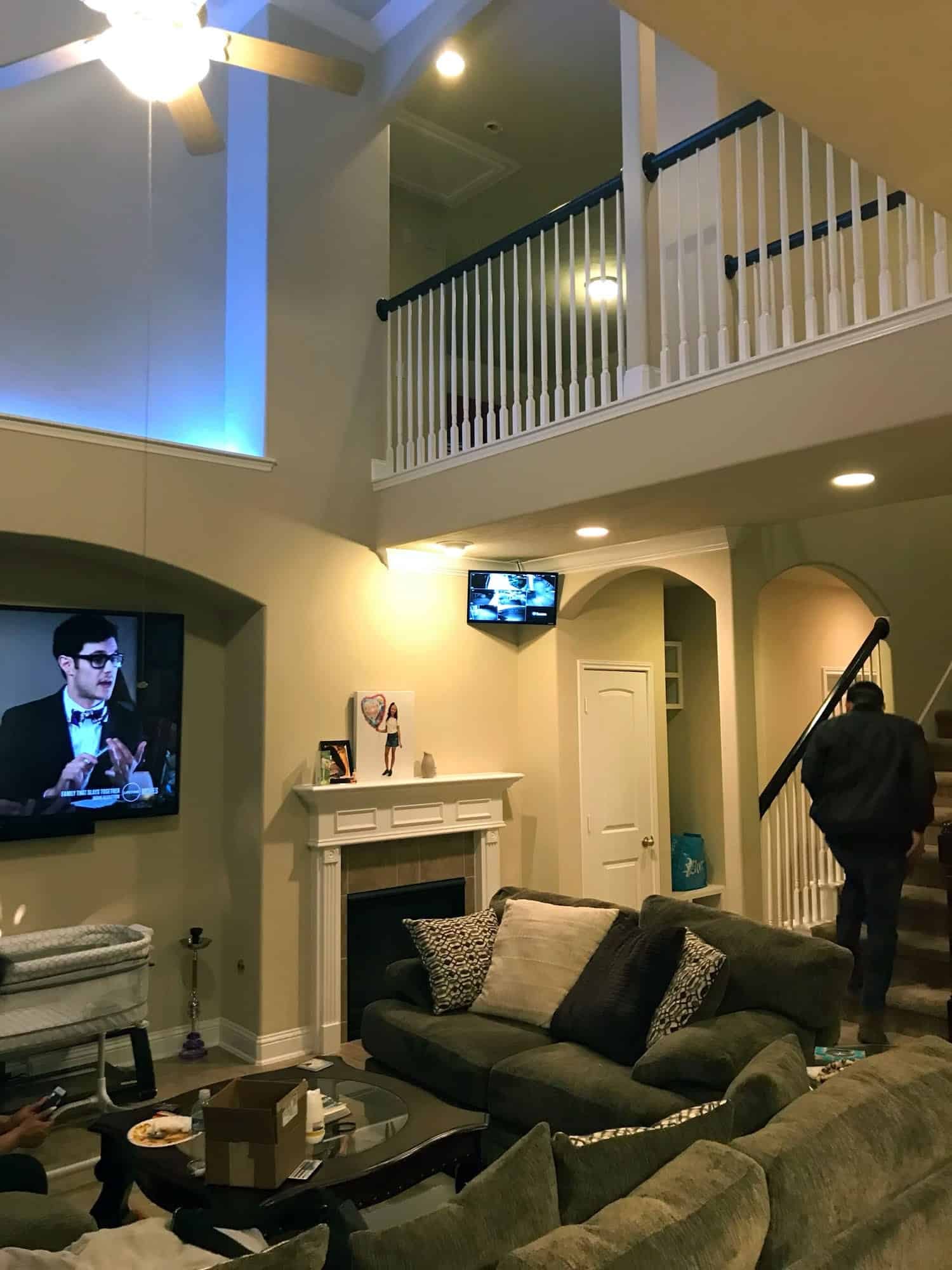 Two-story great room with a TV in a wall alcove and a small security monitor mounted near the staircase