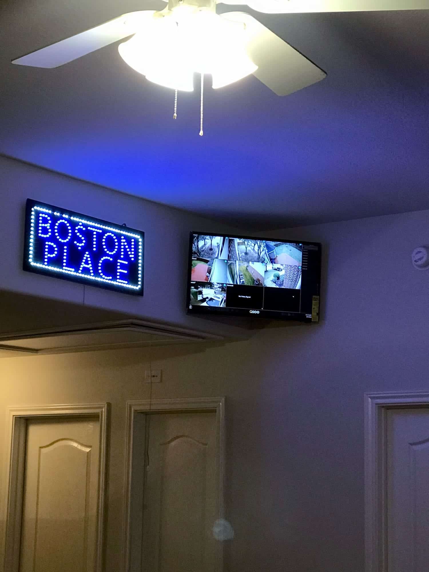 Wall-mounted security monitor showing six camera feeds next to an illuminated sign