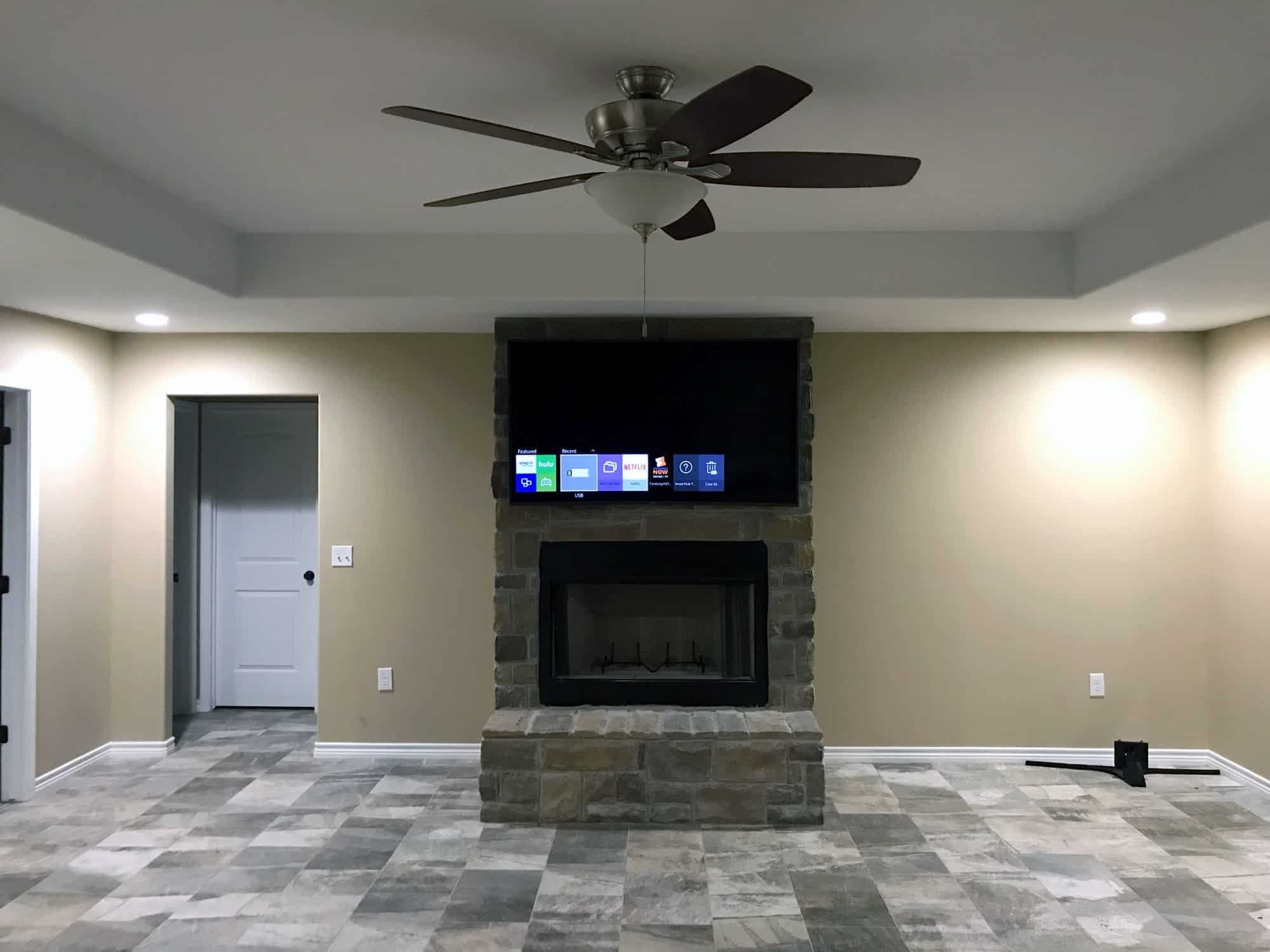 Flat screen TV mounted above a stone fireplace in a family room