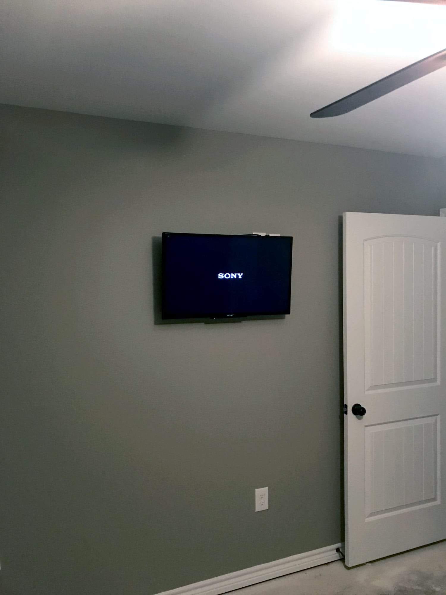 TV mounted on a bedroom wall displaying the Sony startup logo