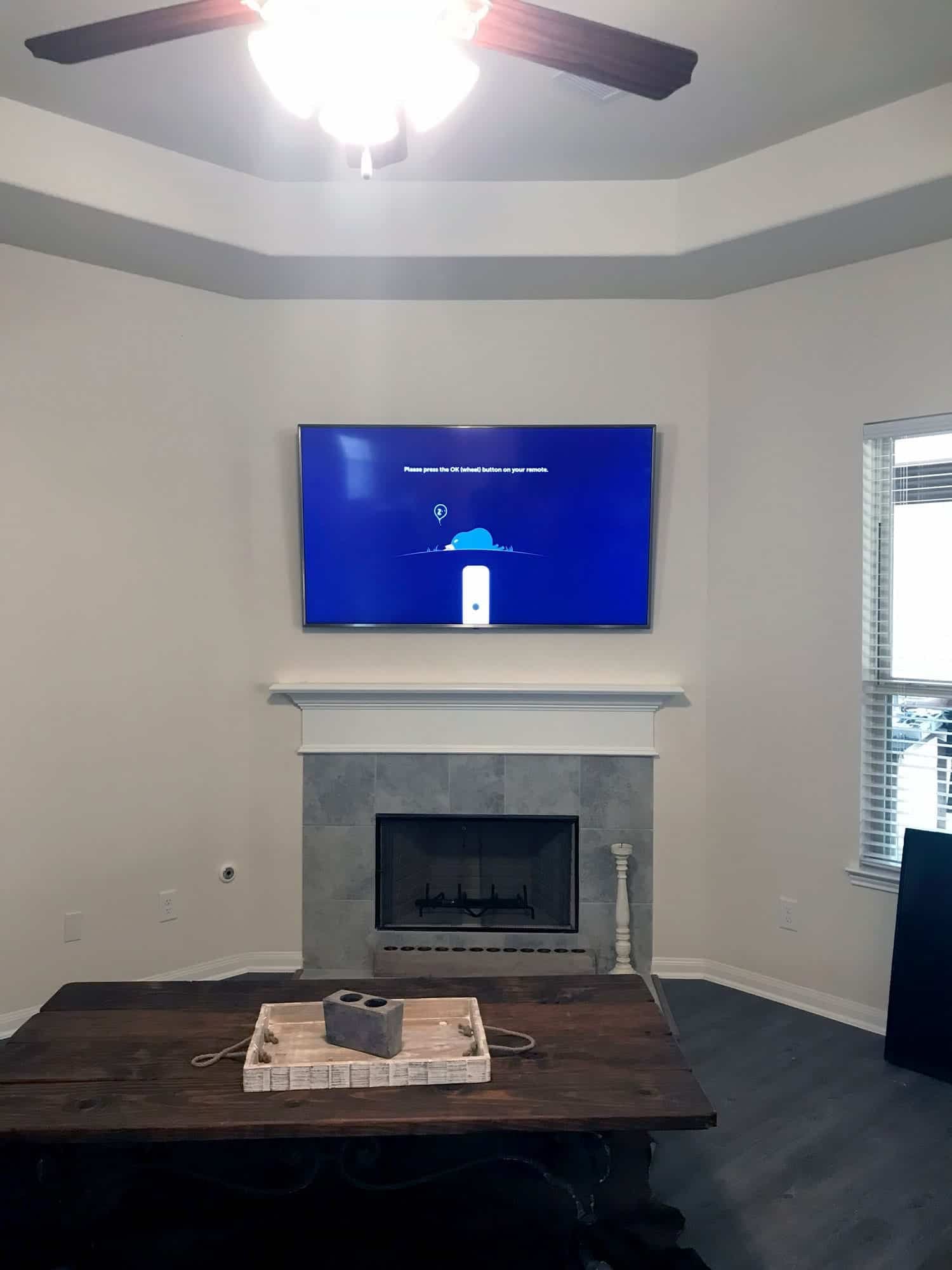 TV mounted above a white fireplace mantel showing a streaming device setup screen