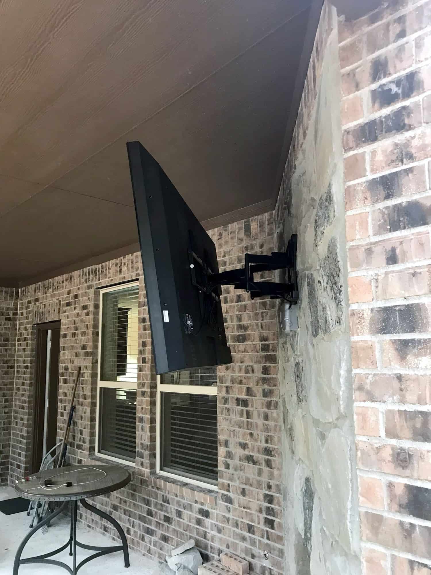 TV on an articulating wall mount folded flat against a brick outdoor column
