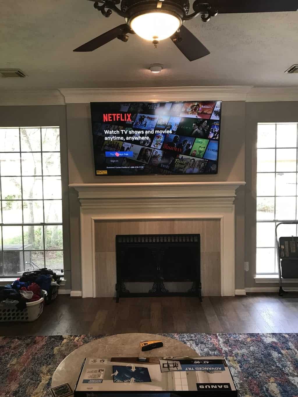 TV mounted above a fireplace displaying the Netflix sign-in screen in a living room